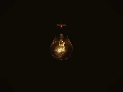 A single light bulb glowing dimly in a dark room