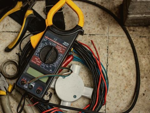 A clamp meter, pliers and electrical cable on a floor