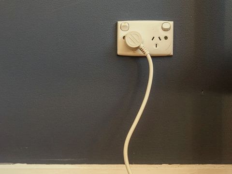 A double power point on a navy wall with a cord plugged in