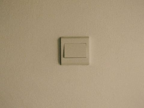 A white light switch on a plain wall